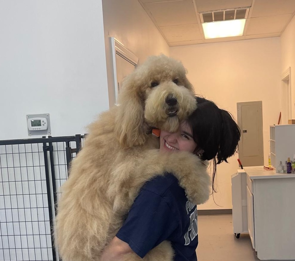 Mariana hugging a large golden Goldendoodle